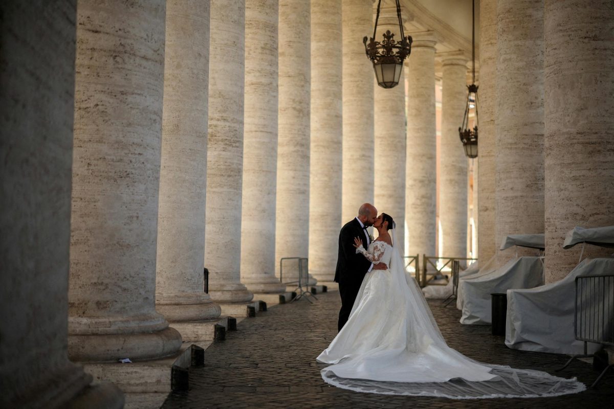 A couple kiss during their wedding photo session under the Vatican colonnade in the Vatican, April 29, 2025. REUTERS/Stoyan Nenov