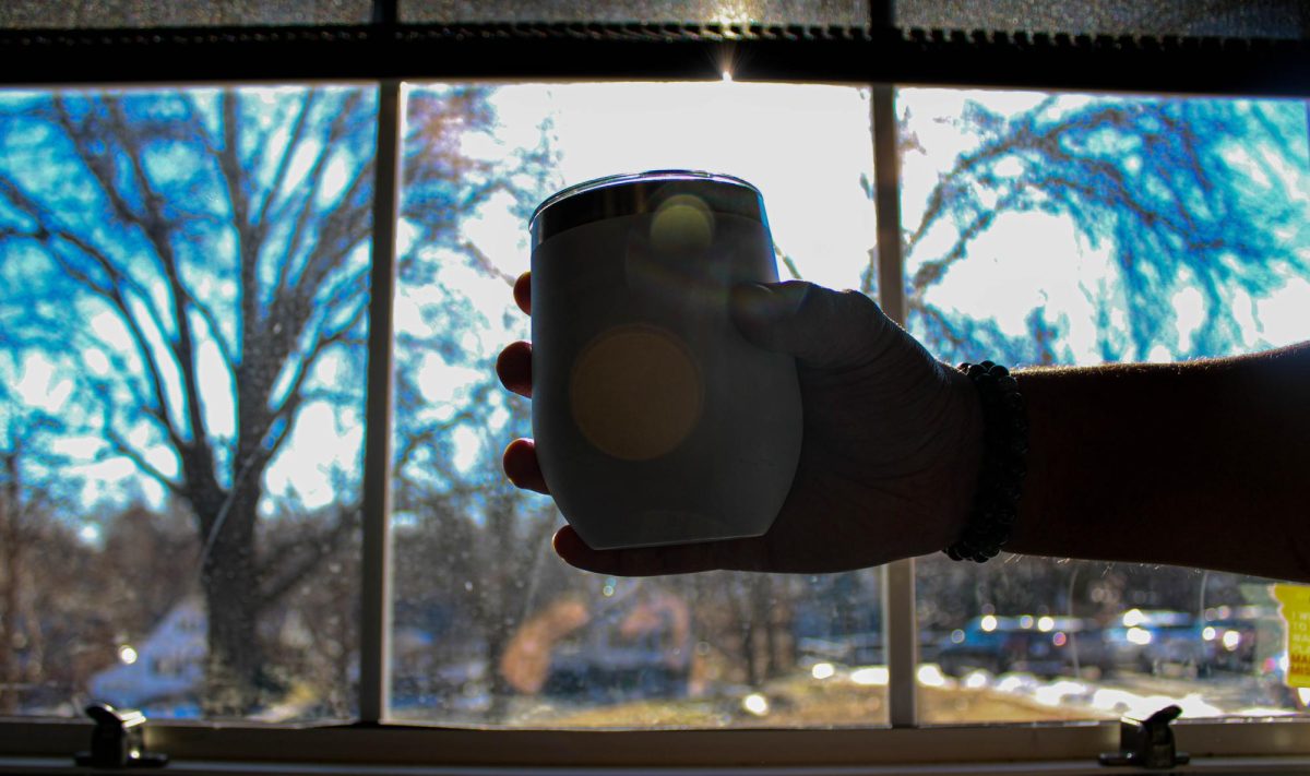 Photo illustration of senior Rakim Hayes holding a cup in a window 
