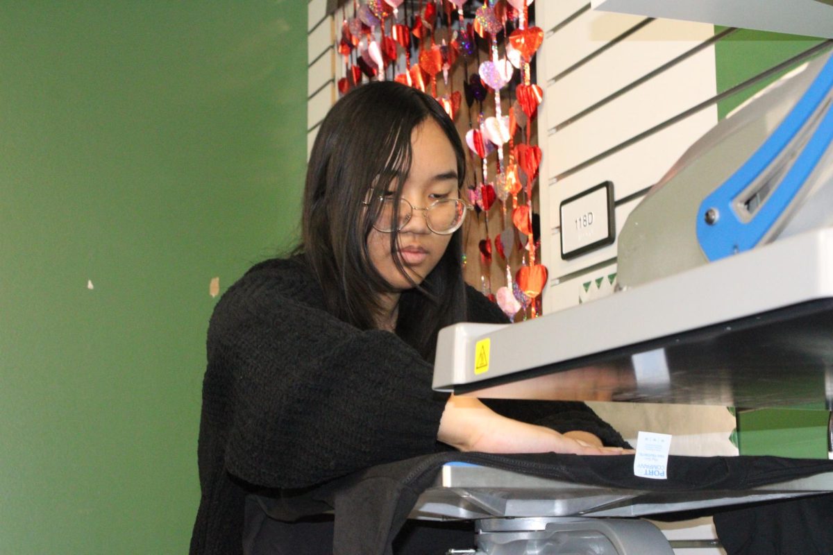 Senior Paw Win works in the school store by heat pressing shirts after receiving a order.