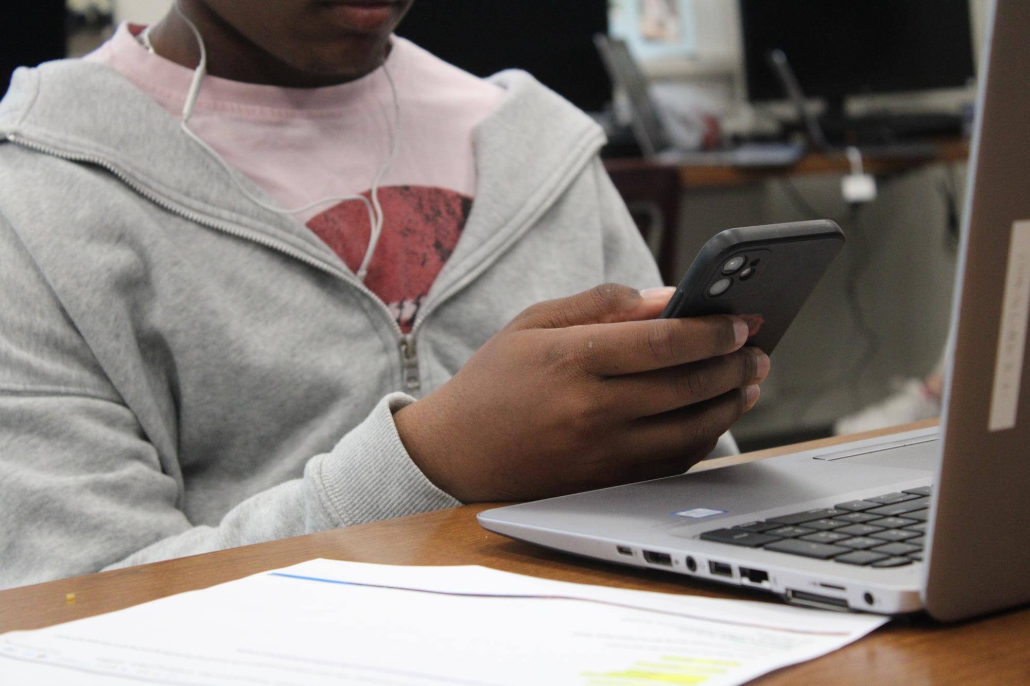 Junior Avant Vaugn puts off his work while looking at his phone.